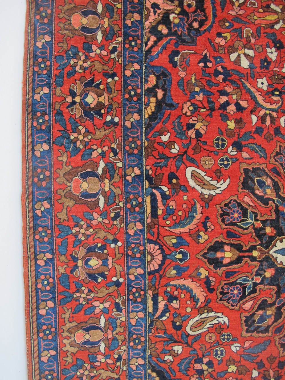 An antique Persian Bakhtiar hand-knotted wool rug featuring a central ivory and blue lobed medallion on a rich red field with floral motifs, surrounded by dark blue spandrels and borders. View XI