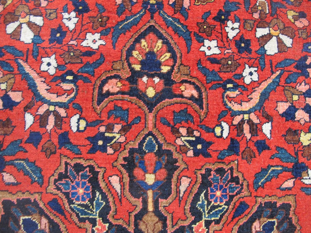 An antique Persian Bakhtiar hand-knotted wool rug featuring a central ivory and blue lobed medallion on a rich red field with floral motifs, surrounded by dark blue spandrels and borders. View XIII