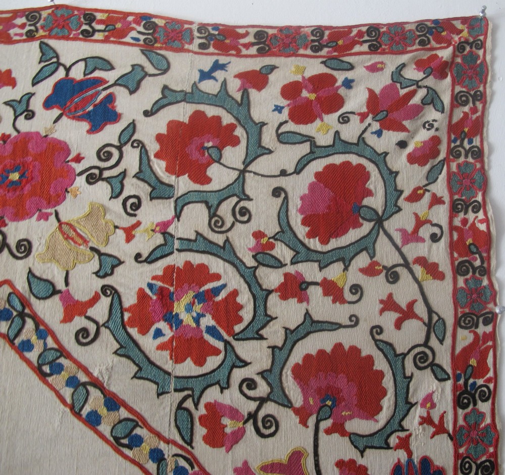 An antique cream cotton suzani textile embroidered with an architectural arch and red floral vines with teal leaves. View VIII