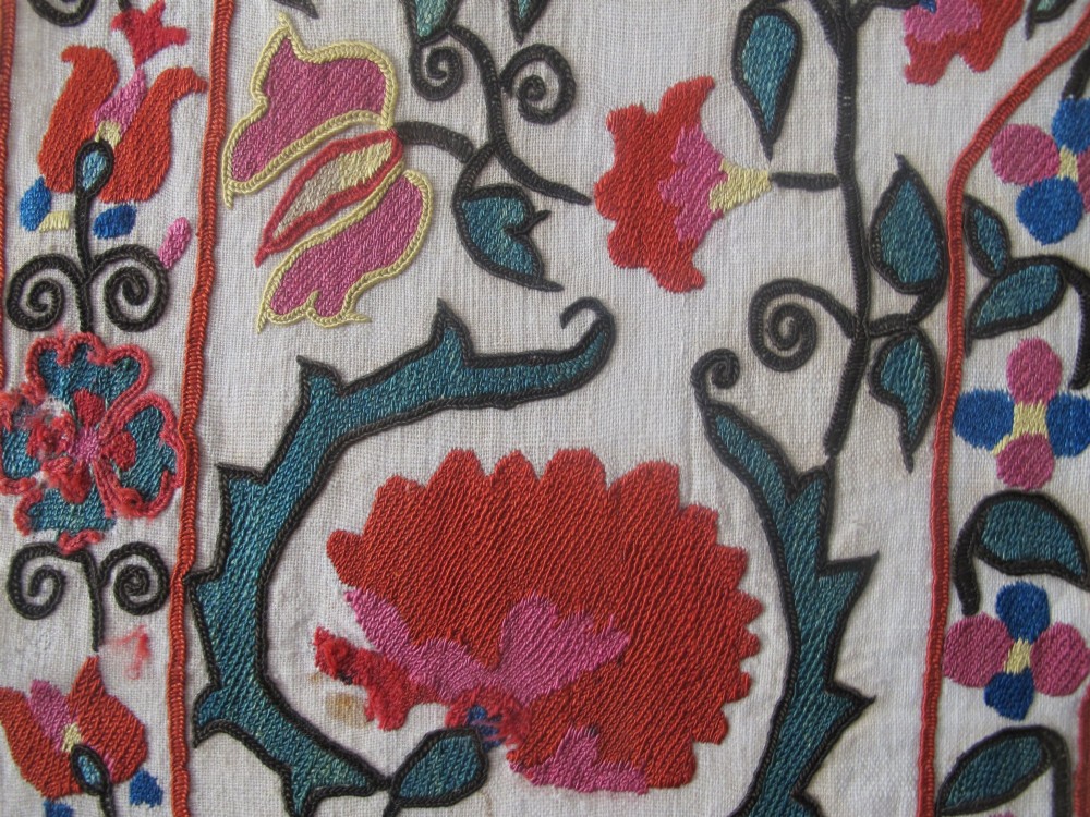 An antique cream cotton suzani textile embroidered with an architectural arch and red floral vines with teal leaves. View XI