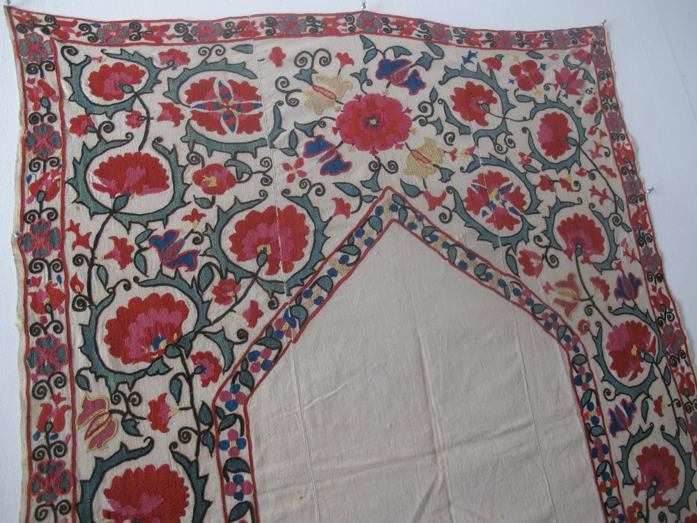 An antique cream cotton suzani textile embroidered with an architectural arch and red floral vines with teal leaves. View XII