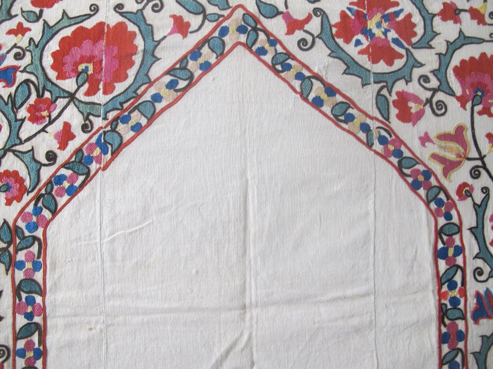 An antique cream cotton suzani textile embroidered with an architectural arch and red floral vines with teal leaves. View XIII
