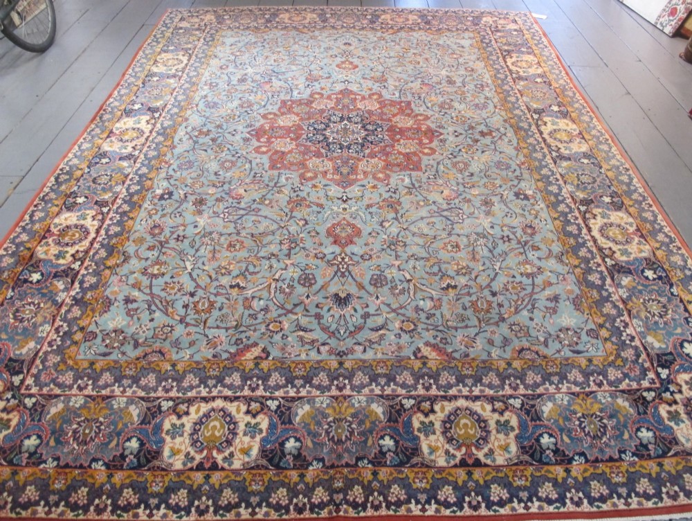 An early twentieth-century hand-knotted Persian Kashan wool carpet featuring a reddish central medallion on a light blue field surrounded by a navy floral border. View II