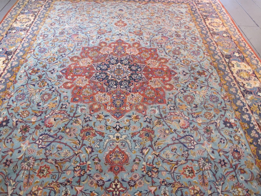 An early twentieth-century hand-knotted Persian Kashan wool carpet featuring a reddish central medallion on a light blue field surrounded by a navy floral border. View III
