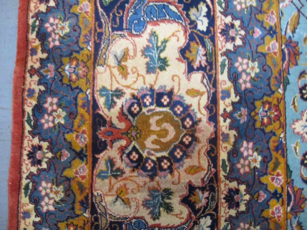 An early twentieth-century hand-knotted Persian Kashan wool carpet featuring a reddish central medallion on a light blue field surrounded by a navy floral border. View IV