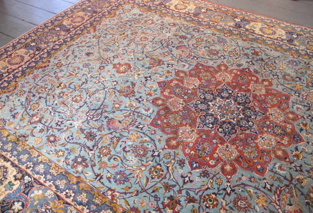 An early twentieth-century hand-knotted Persian Kashan wool carpet featuring a reddish central medallion on a light blue field surrounded by a navy floral border. View VII