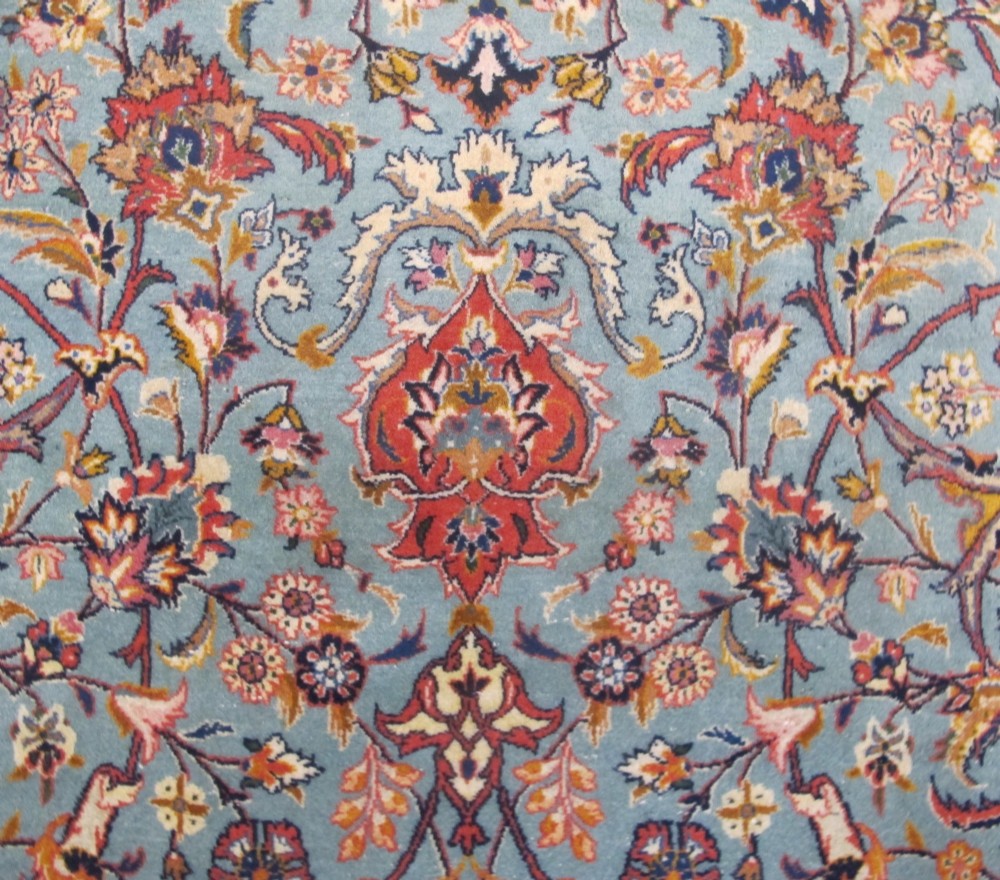 An early twentieth-century hand-knotted Persian Kashan wool carpet featuring a reddish central medallion on a light blue field surrounded by a navy floral border. View XI