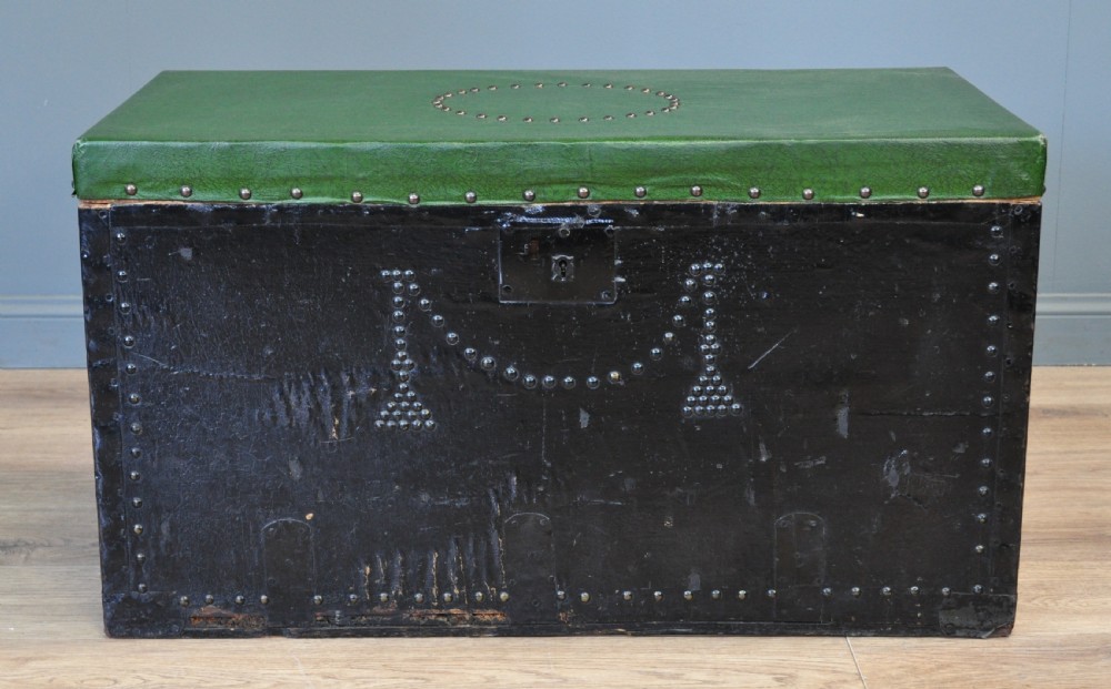 A rectangular Victorian pine kist chest featuring a black painted exterior decorated with brass studwork and a green padded top.
