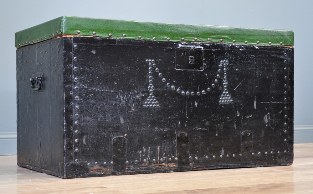 A rectangular Victorian pine kist chest featuring a black painted exterior decorated with brass studwork and a green padded top. View II