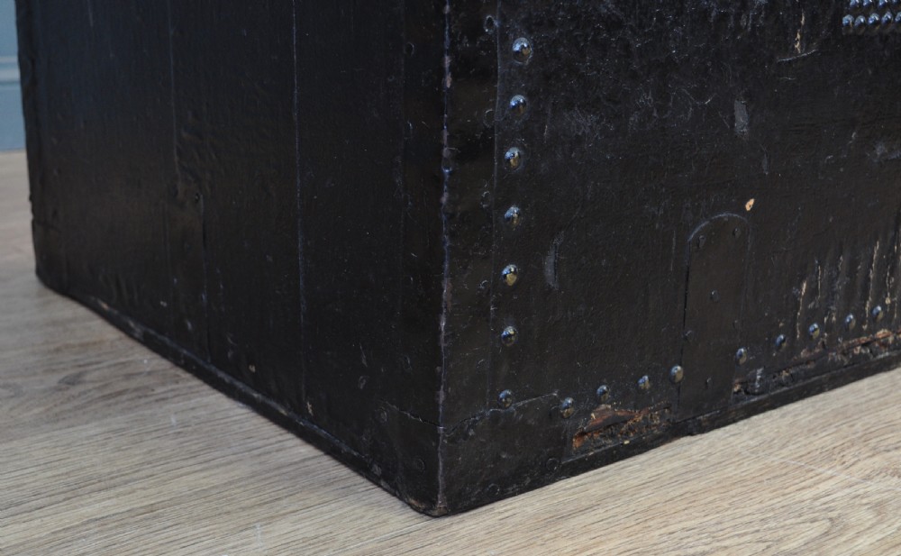 A rectangular Victorian pine kist chest featuring a black painted exterior decorated with brass studwork and a green padded top. View IV