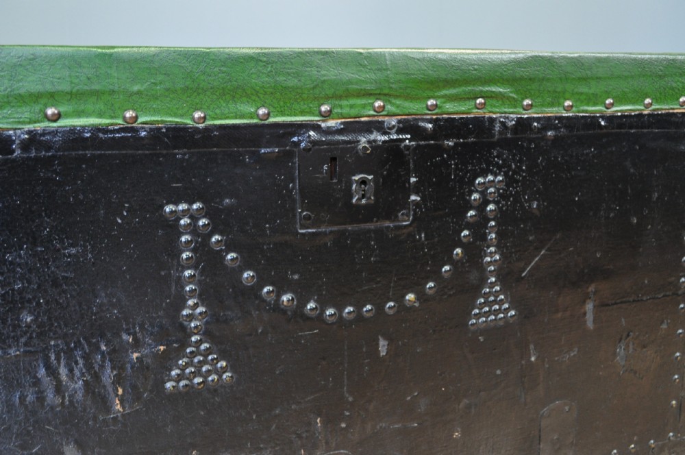 A rectangular Victorian pine kist chest featuring a black painted exterior decorated with brass studwork and a green padded top. View VI