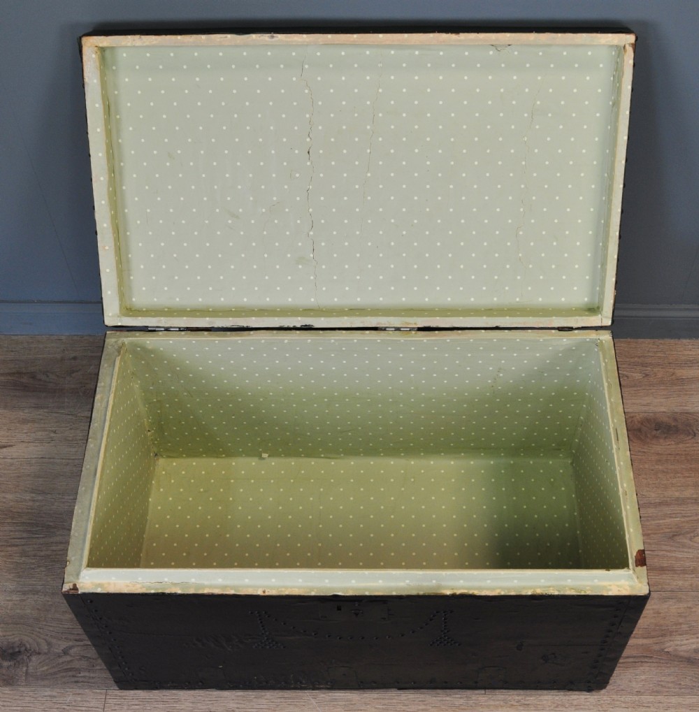 A rectangular Victorian pine kist chest featuring a black painted exterior decorated with brass studwork and a green padded top. View VII