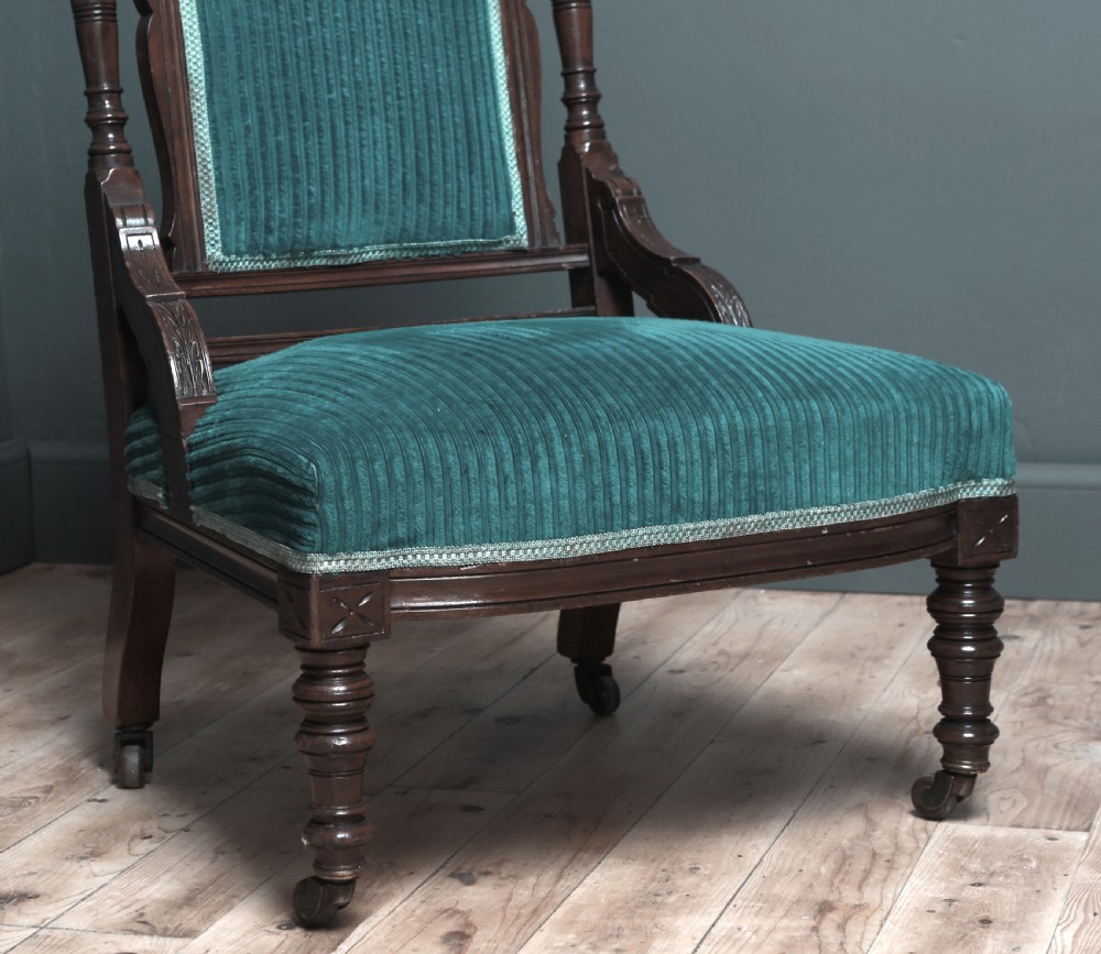 A Victorian carved walnut fireside chair featuring green corded upholstery, turned legs on castors, and decorative backrest details. View III