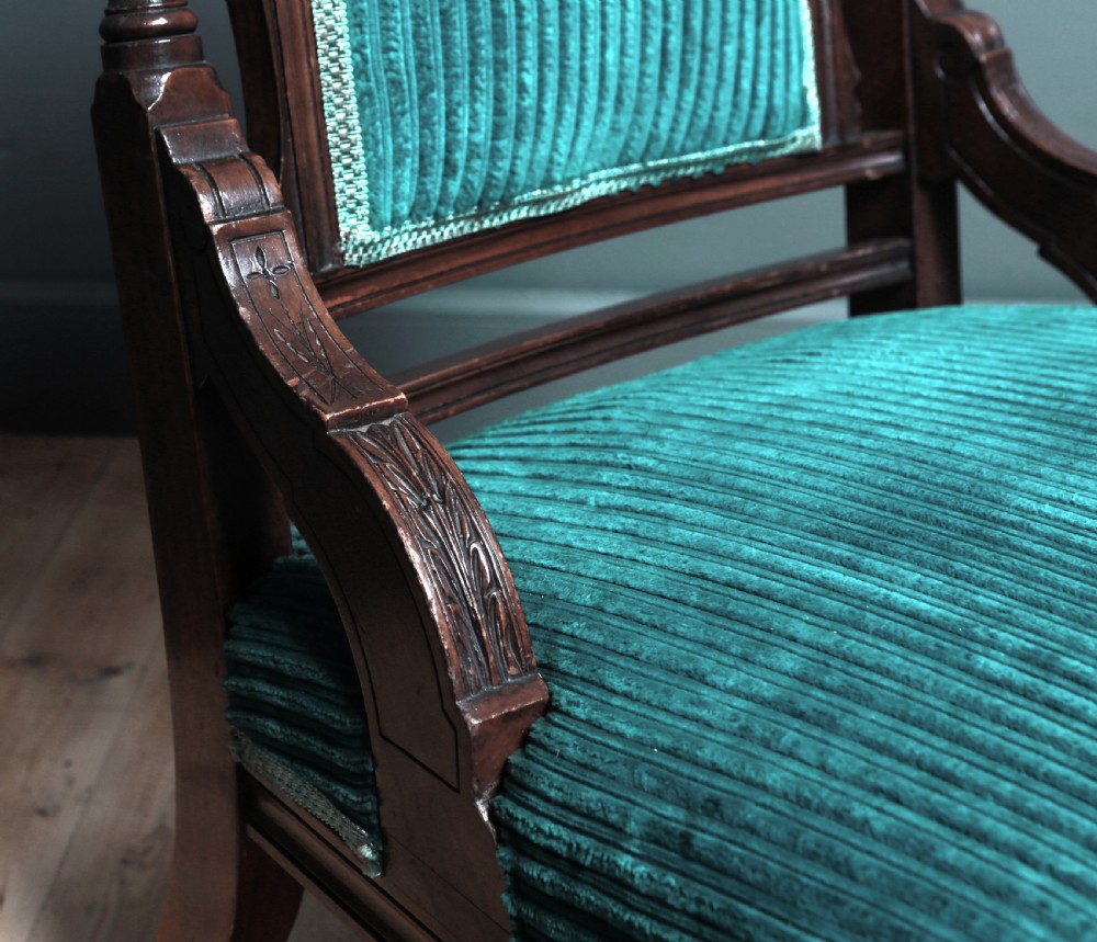 A Victorian carved walnut fireside chair featuring green corded upholstery, turned legs on castors, and decorative backrest details. View VI
