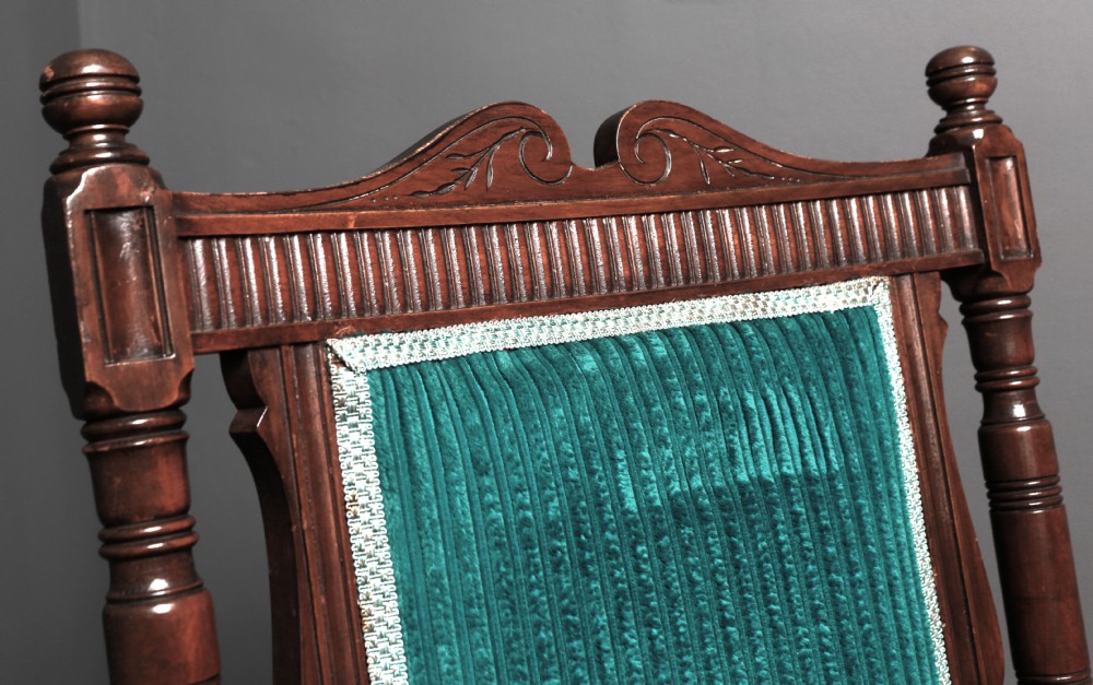 A Victorian carved walnut fireside chair featuring green corded upholstery, turned legs on castors, and decorative backrest details. View IX