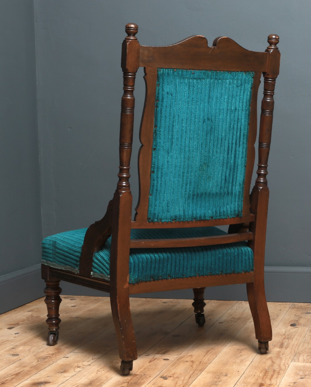 A Victorian carved walnut fireside chair featuring green corded upholstery, turned legs on castors, and decorative backrest details. View X