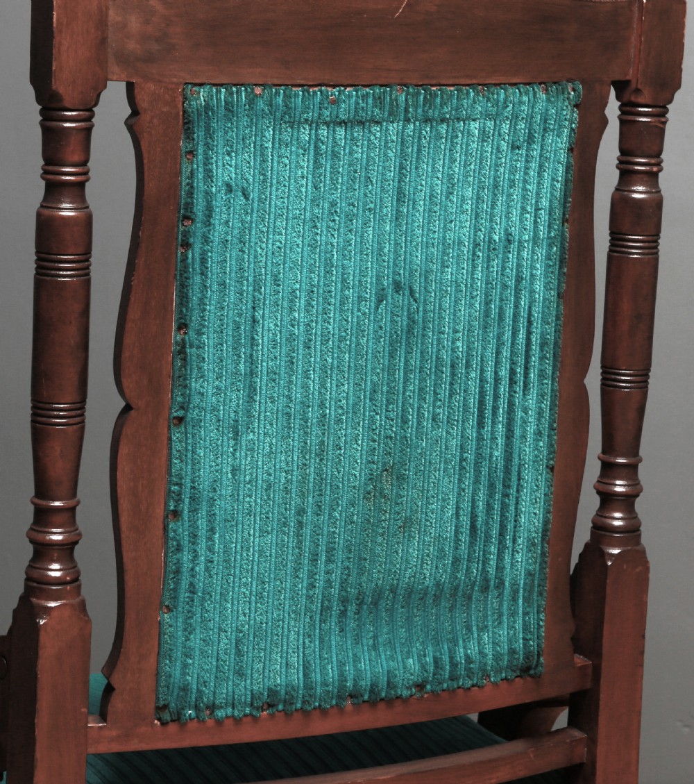 A Victorian carved walnut fireside chair featuring green corded upholstery, turned legs on castors, and decorative backrest details. View XI