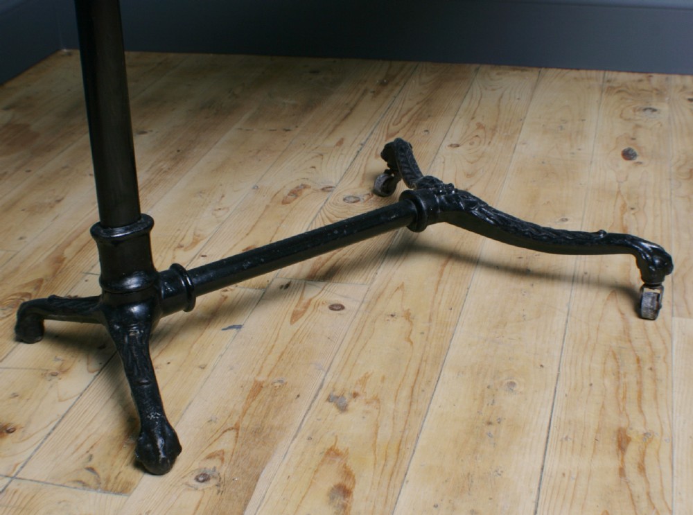 A Victorian cast iron adjustable overbed table featuring a black pedestal stand with castors, a tilting wooden top edged with studding, metal page clips, and a small side tray. View IV