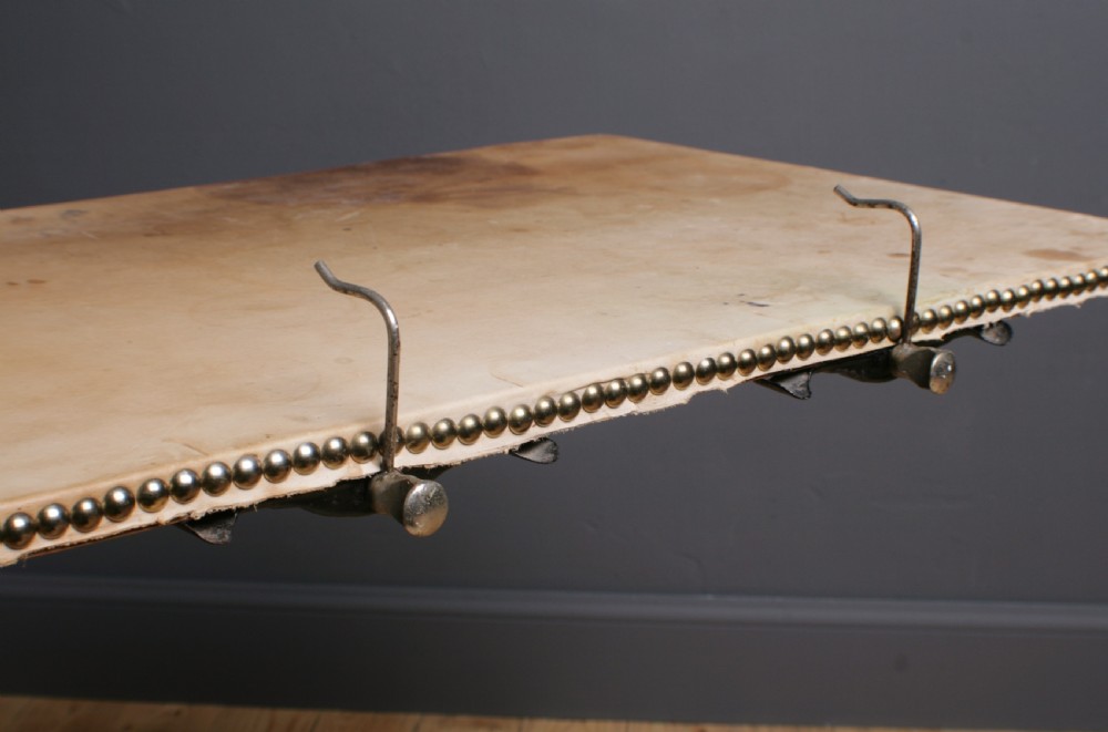 A Victorian cast iron adjustable overbed table featuring a black pedestal stand with castors, a tilting wooden top edged with studding, metal page clips, and a small side tray. View VII