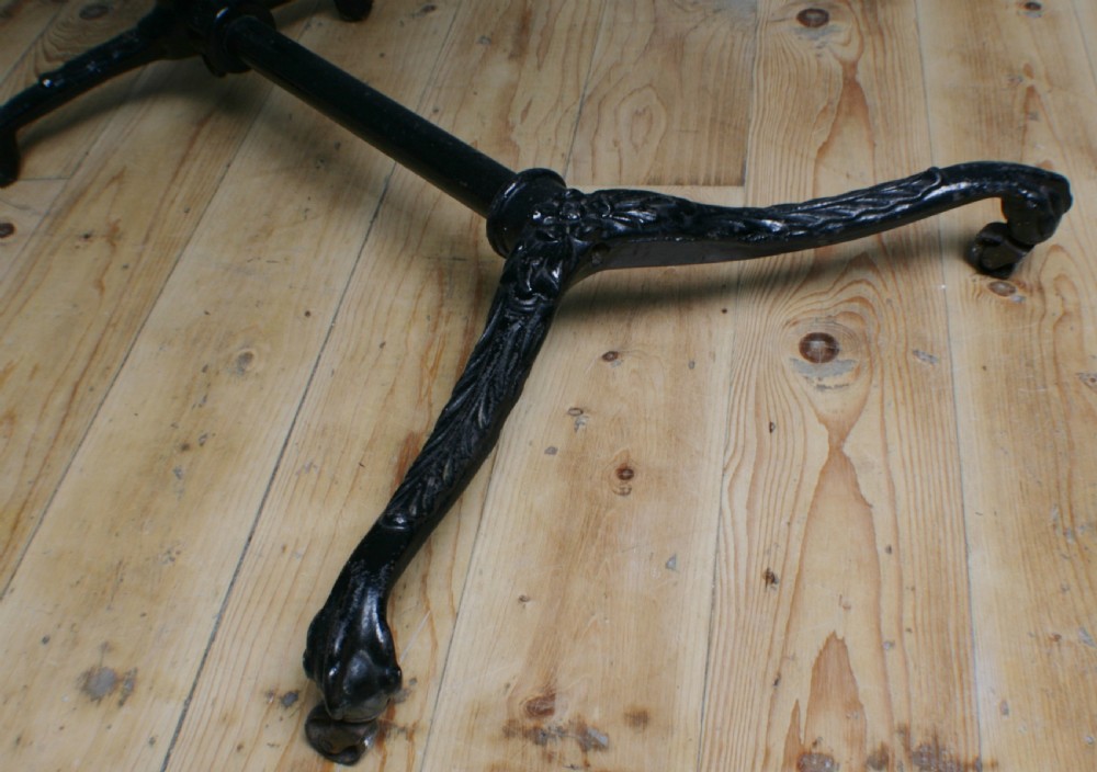 A Victorian cast iron adjustable overbed table featuring a black pedestal stand with castors, a tilting wooden top edged with studding, metal page clips, and a small side tray. View X