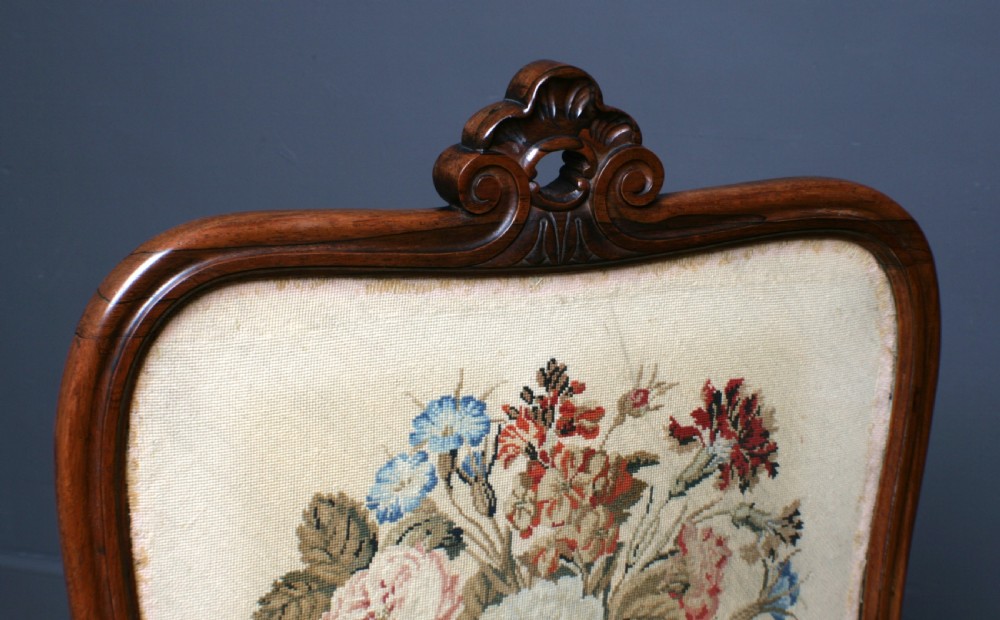 A Victorian rosewood fire screen with a carved top cresting framing a central floral needlepoint tapestry panel. View IV