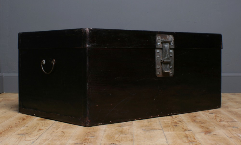A large rectangular black lacquered oriental pigskin shipping trunk featuring a central metal latch plate. View II