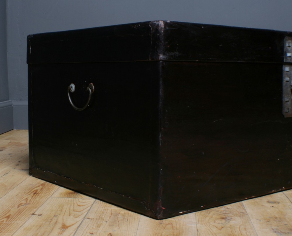 A large rectangular black lacquered oriental pigskin shipping trunk featuring a central metal latch plate. View III