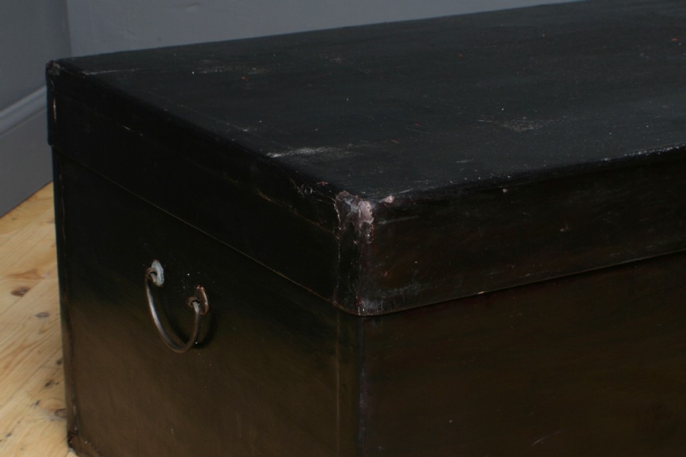 A large rectangular black lacquered oriental pigskin shipping trunk featuring a central metal latch plate. View IV