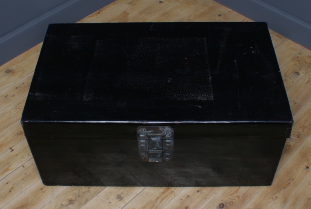A large rectangular black lacquered oriental pigskin shipping trunk featuring a central metal latch plate. View VI