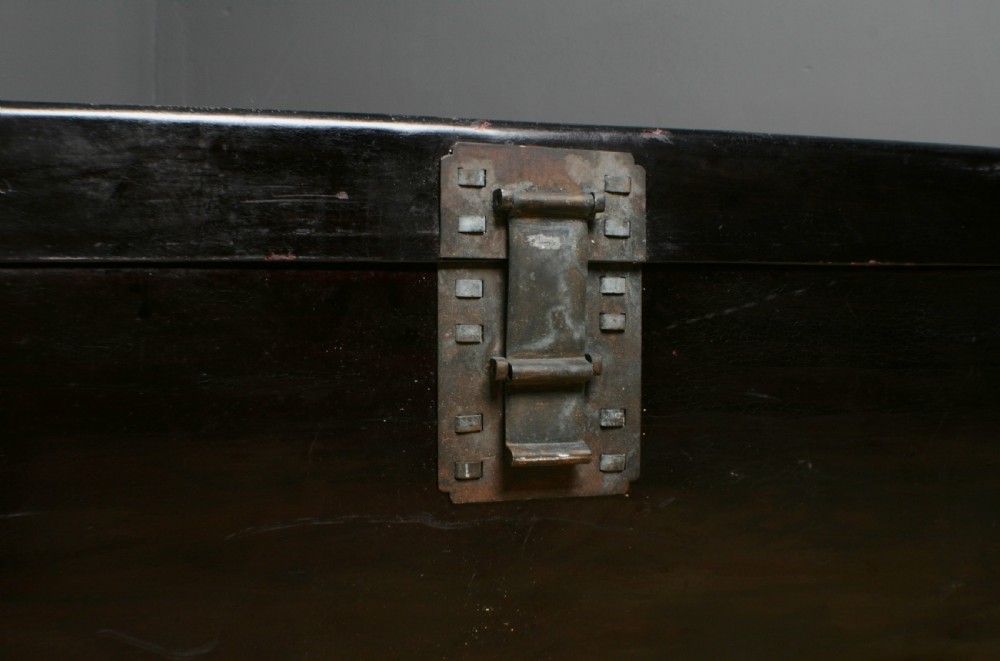 A large rectangular black lacquered oriental pigskin shipping trunk featuring a central metal latch plate. View X