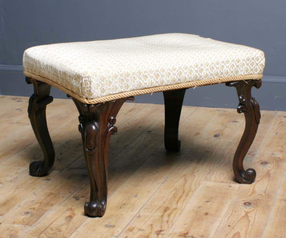 A Victorian rosewood footstool with carved cabriole legs and a cream patterned fabric seat. View II