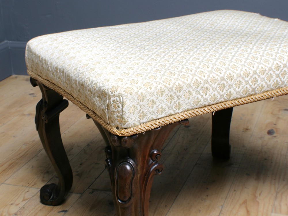 A Victorian rosewood footstool with carved cabriole legs and a cream patterned fabric seat. View III