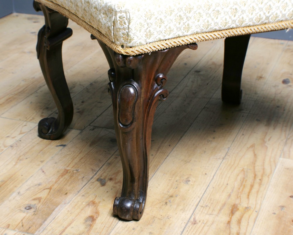 A Victorian rosewood footstool with carved cabriole legs and a cream patterned fabric seat. View IV