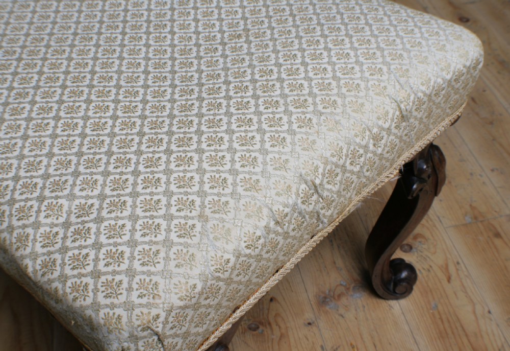 A Victorian rosewood footstool with carved cabriole legs and a cream patterned fabric seat. View VI