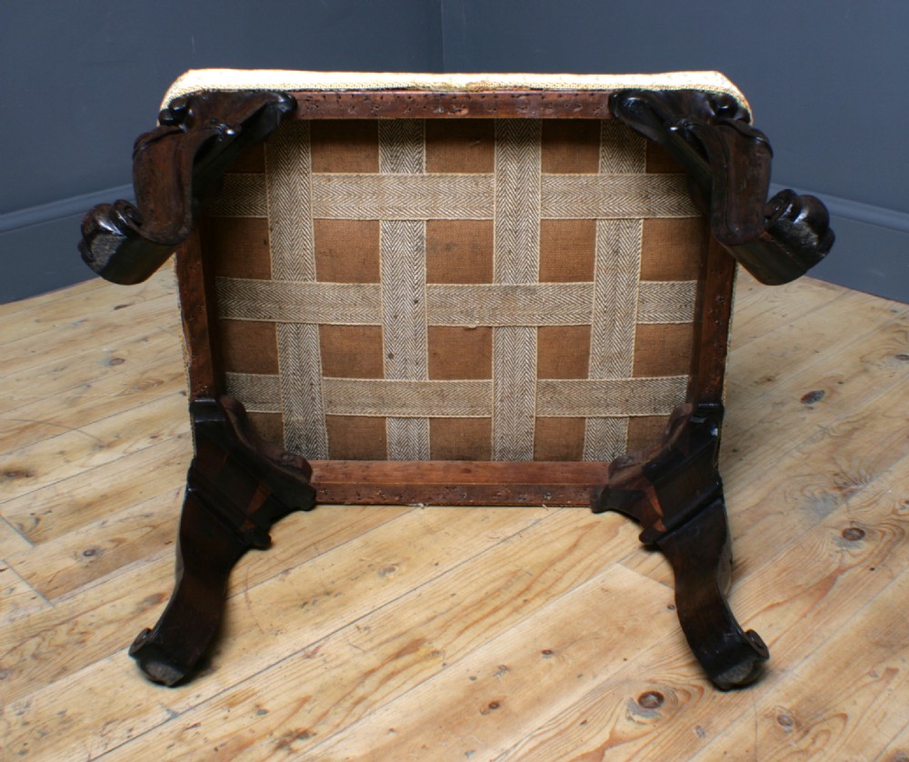 A Victorian rosewood footstool with carved cabriole legs and a cream patterned fabric seat. View IX