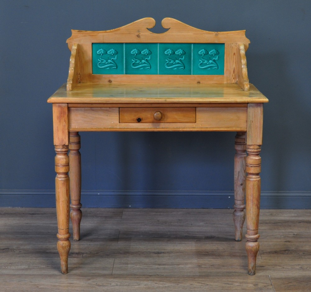 An antique Victorian pine washstand featuring a raised gallery splashback set with four green embossed tiles, a single frieze drawer, and turned legs. View II
