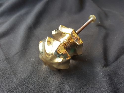 fig 1. A polished brass centre door knob featuring a multi-fluted star shape with an attached threaded mounting bolt.