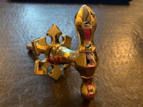 fig 1. A polished brass Victorian centre door knob featuring a pointed T-bar handle and an ornate star-shaped rosette backplate with a threaded mounting bolt.