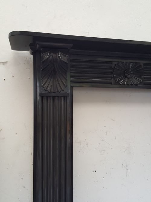 fig 1. A black Victorian Welsh slate fireplace surround featuring fluted side jambs, carved fan brackets, and a central floral rosette motif.