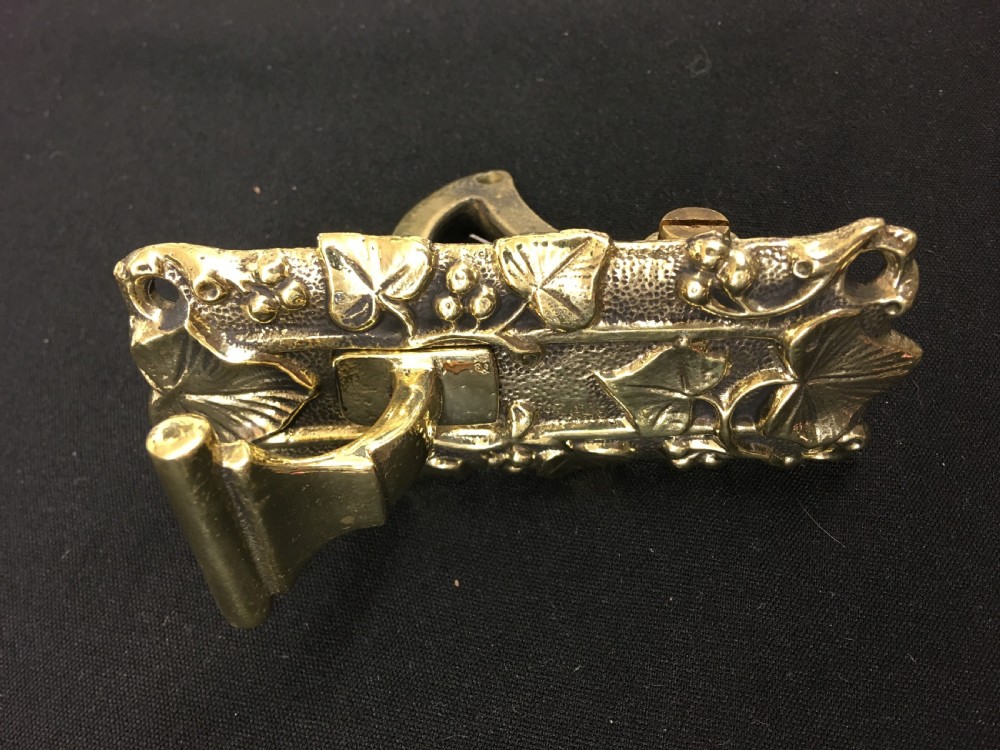 A cast brass Victorian door bell pull featuring intricate relief ivy leaf and berry detailing with a central mechanical lever.