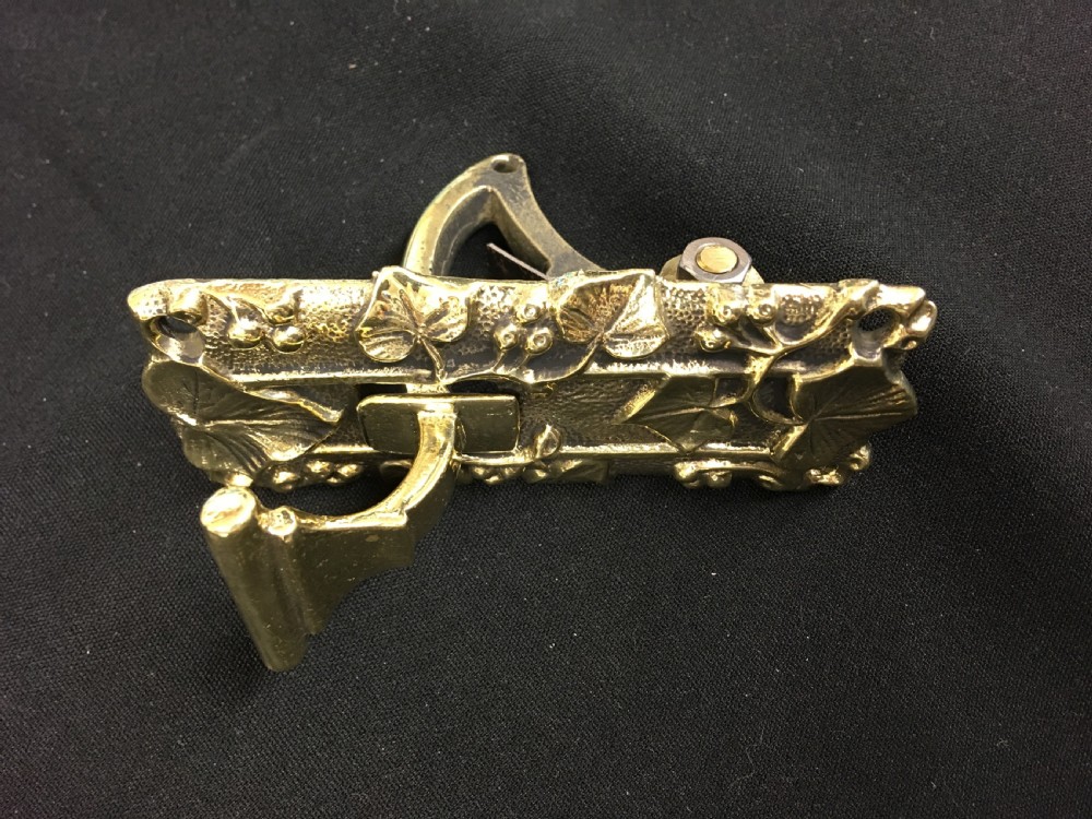 A cast brass Victorian door bell pull featuring intricate relief ivy leaf and berry detailing with a central mechanical lever. View V