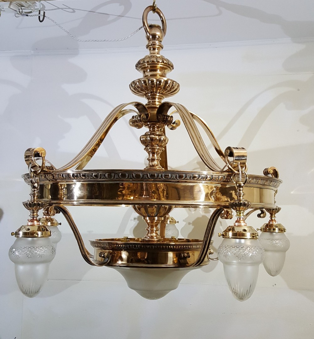 A Victorian style polished bronze and brass ceiling light fixture featuring a central ring frame with scrolled upper supports and frosted cut glass shades.