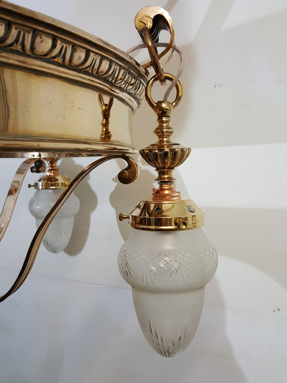 A Victorian style polished bronze and brass ceiling light fixture featuring a central ring frame with scrolled upper supports and frosted cut glass shades. View VI