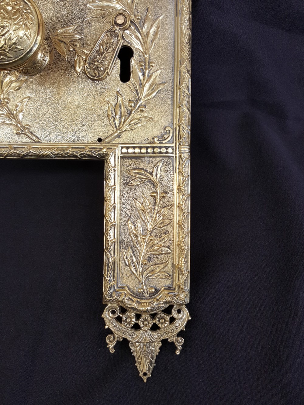 An ornate Regency period cast brass door plate featuring raised botanical leaf decoration, a round decorative door knob, a keyhole escutcheon, and ornate cresting. View IV