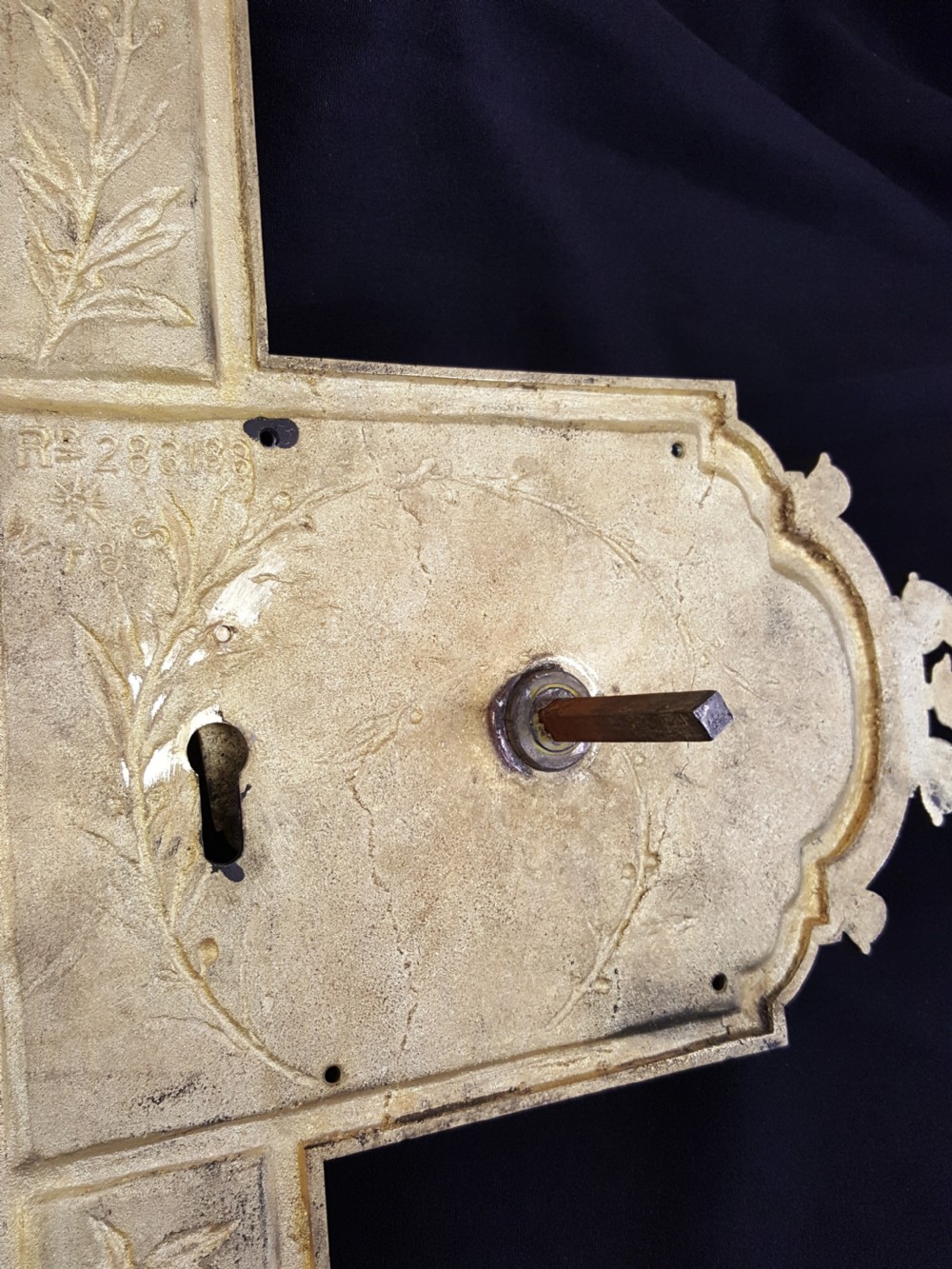 An ornate Regency period cast brass door plate featuring raised botanical leaf decoration, a round decorative door knob, a keyhole escutcheon, and ornate cresting. View V