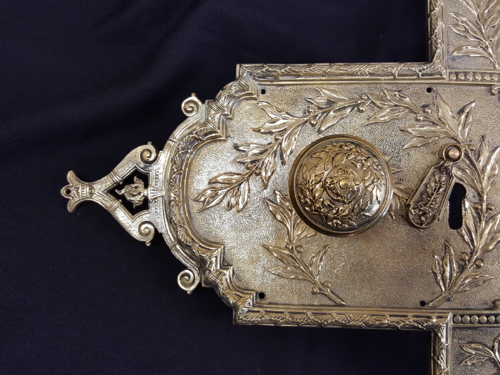An ornate Regency period cast brass door plate featuring raised botanical leaf decoration, a round decorative door knob, a keyhole escutcheon, and ornate cresting. View VII
