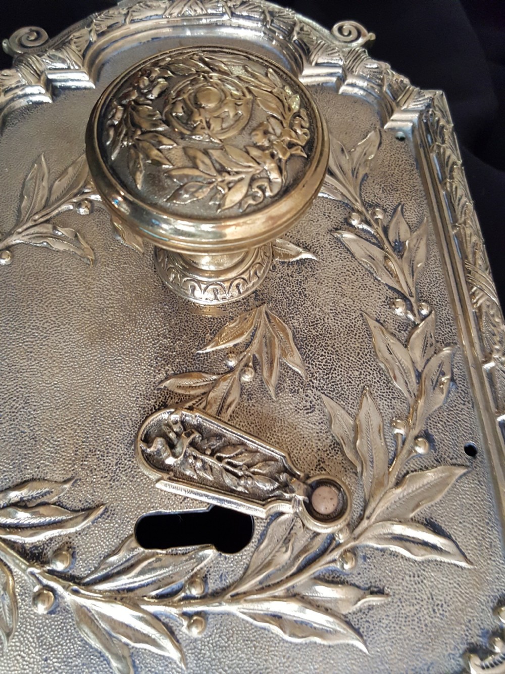An ornate Regency period cast brass door plate featuring raised botanical leaf decoration, a round decorative door knob, a keyhole escutcheon, and ornate cresting. View IX