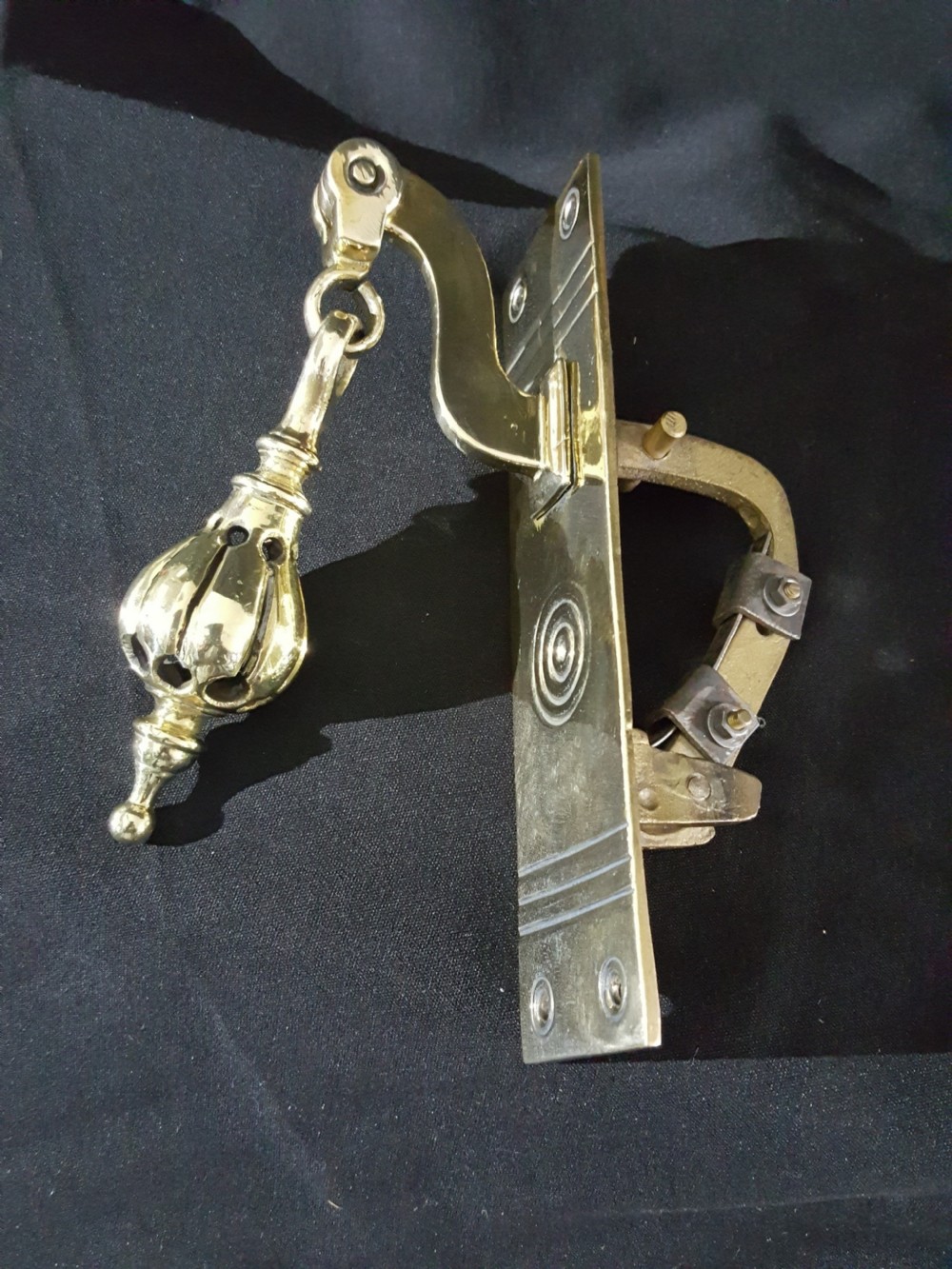 A polished brass Georgian style pull bell mechanism featuring an openwork teardrop handle and rectangular backplate with mounting holes. View II