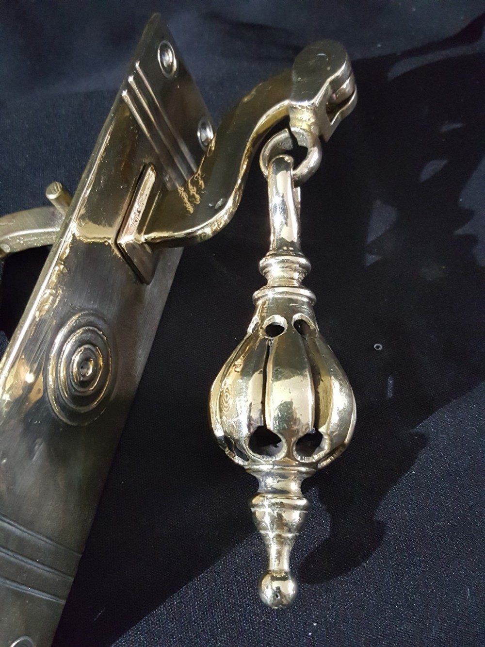 A polished brass Georgian style pull bell mechanism featuring an openwork teardrop handle and rectangular backplate with mounting holes. View V