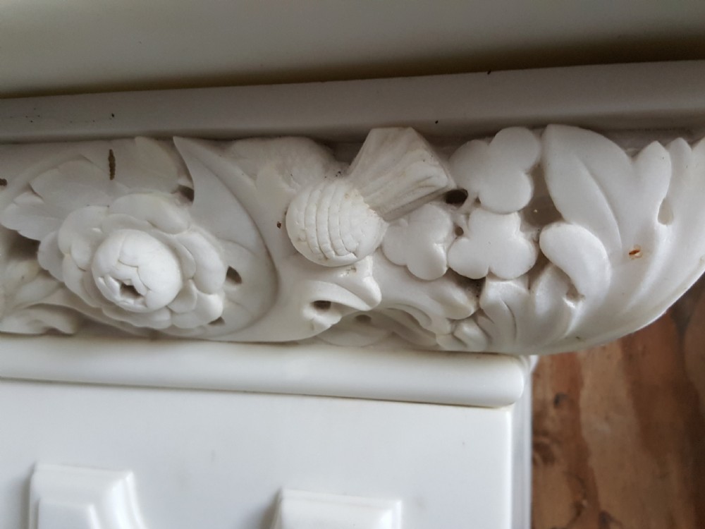 A carved white statuary marble Victorian fireplace surround featuring an ornate floral frieze and moulded arched jambs. View II
